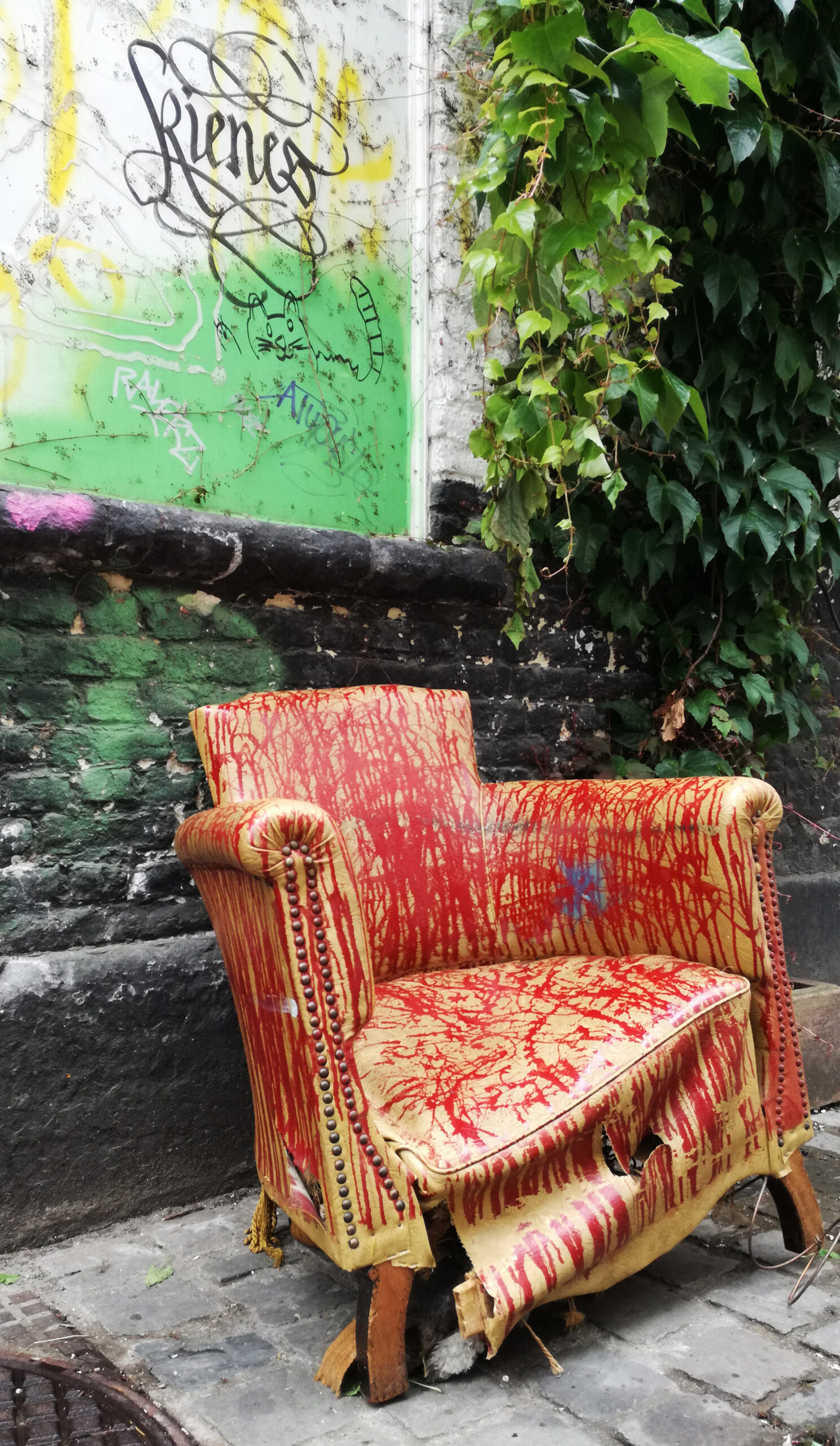 fauteuil abimé tranant dans une rue de Bruxelles, avec des grafitis.